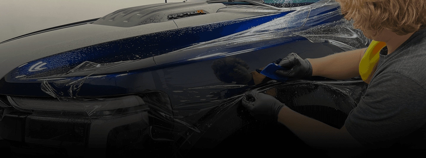 Installer wrapping a car in blue vinyl, highlighting Speed Shield USA's expertise in paint protection and vehicle wraps