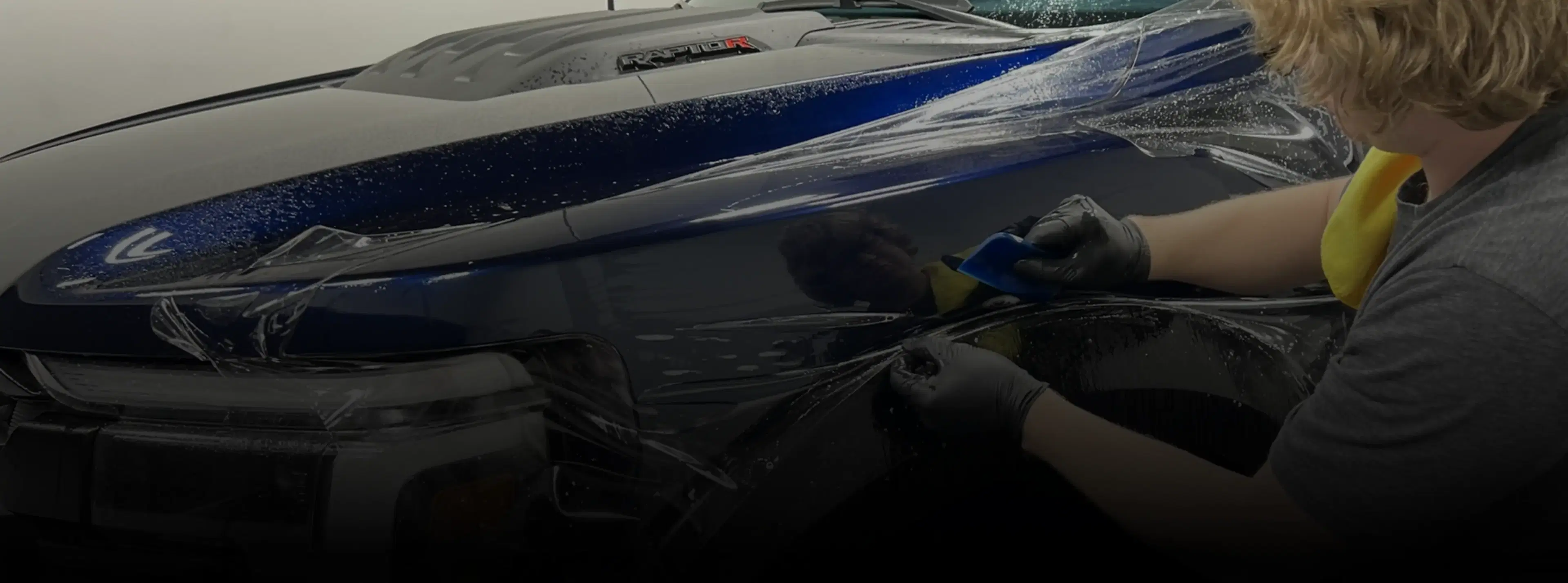 Installer wrapping a car in blue vinyl, highlighting Speed Shield USA's expertise in paint protection and vehicle wrap