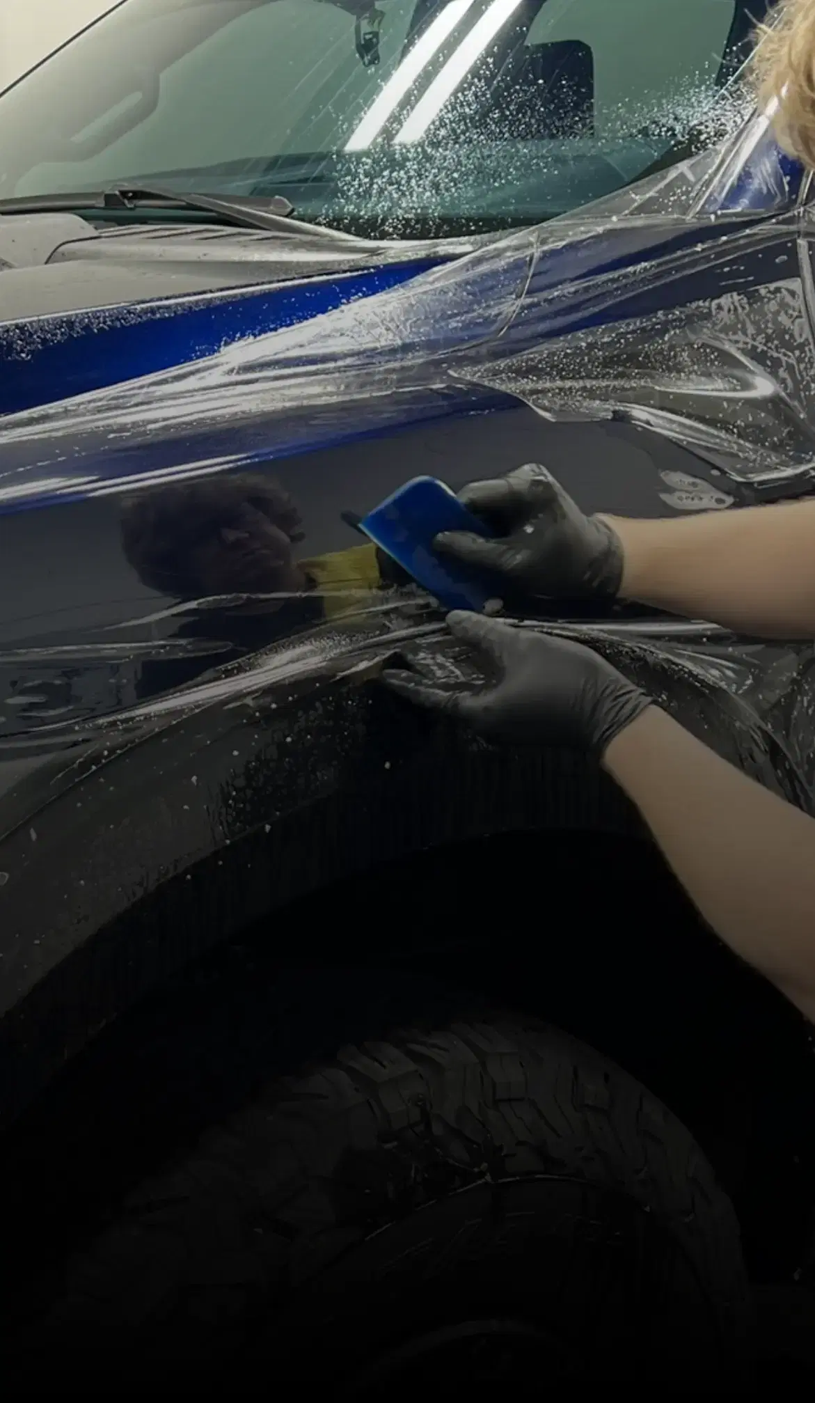 Installer wrapping a car in blue vinyl, highlighting Speed Shield USA's expertise in paint protection and vehicle wrap