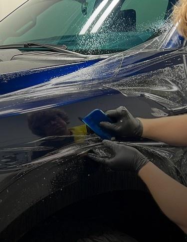Installer wrapping a car in blue vinyl, highlighting Speed Shield USA's expertise in paint protection and vehicle wraps.