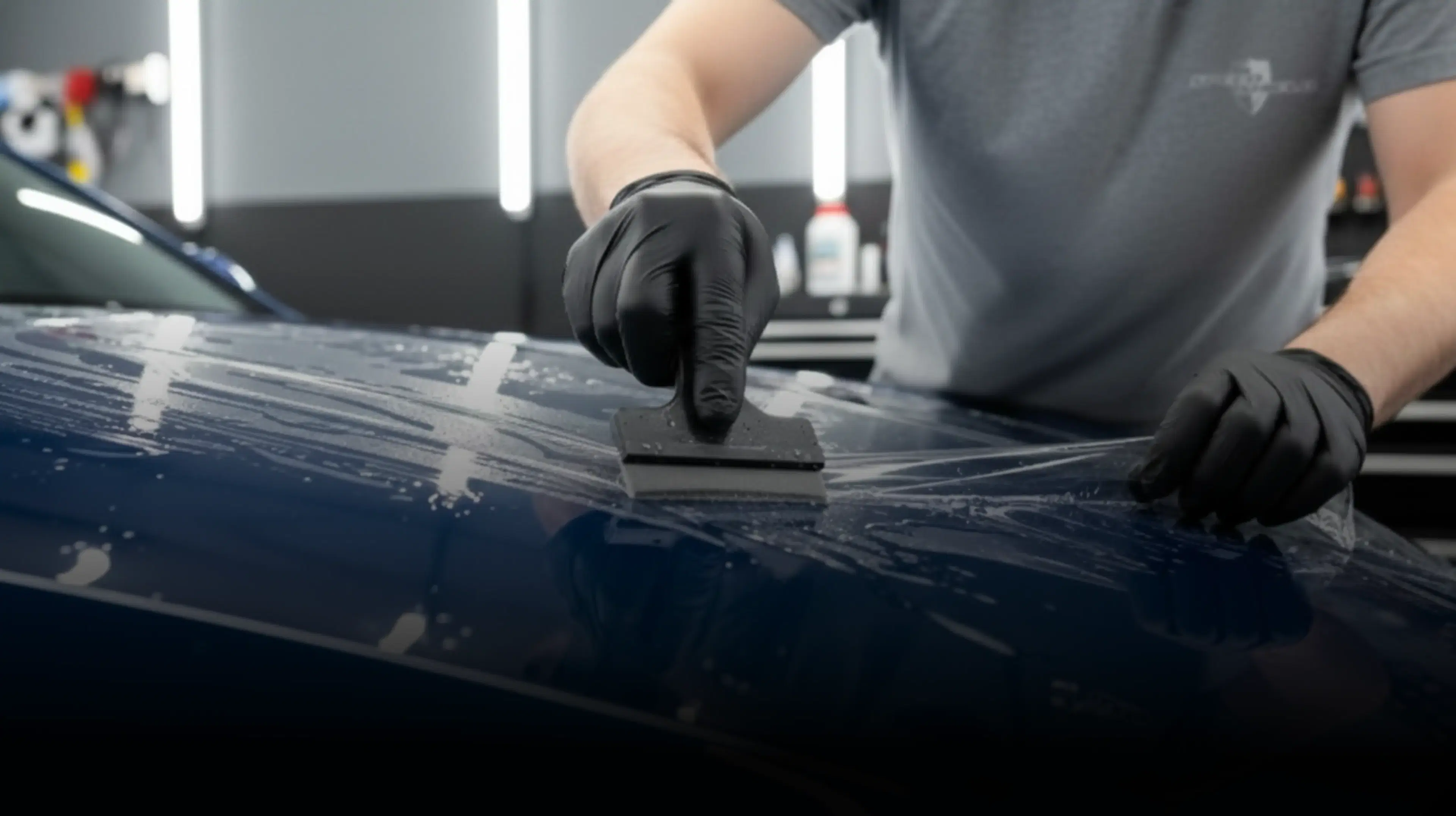 Installer wrapping a car in blue vehicle, highlighting Speed Shield USA's expertise in paint protection and vehicle wraps.