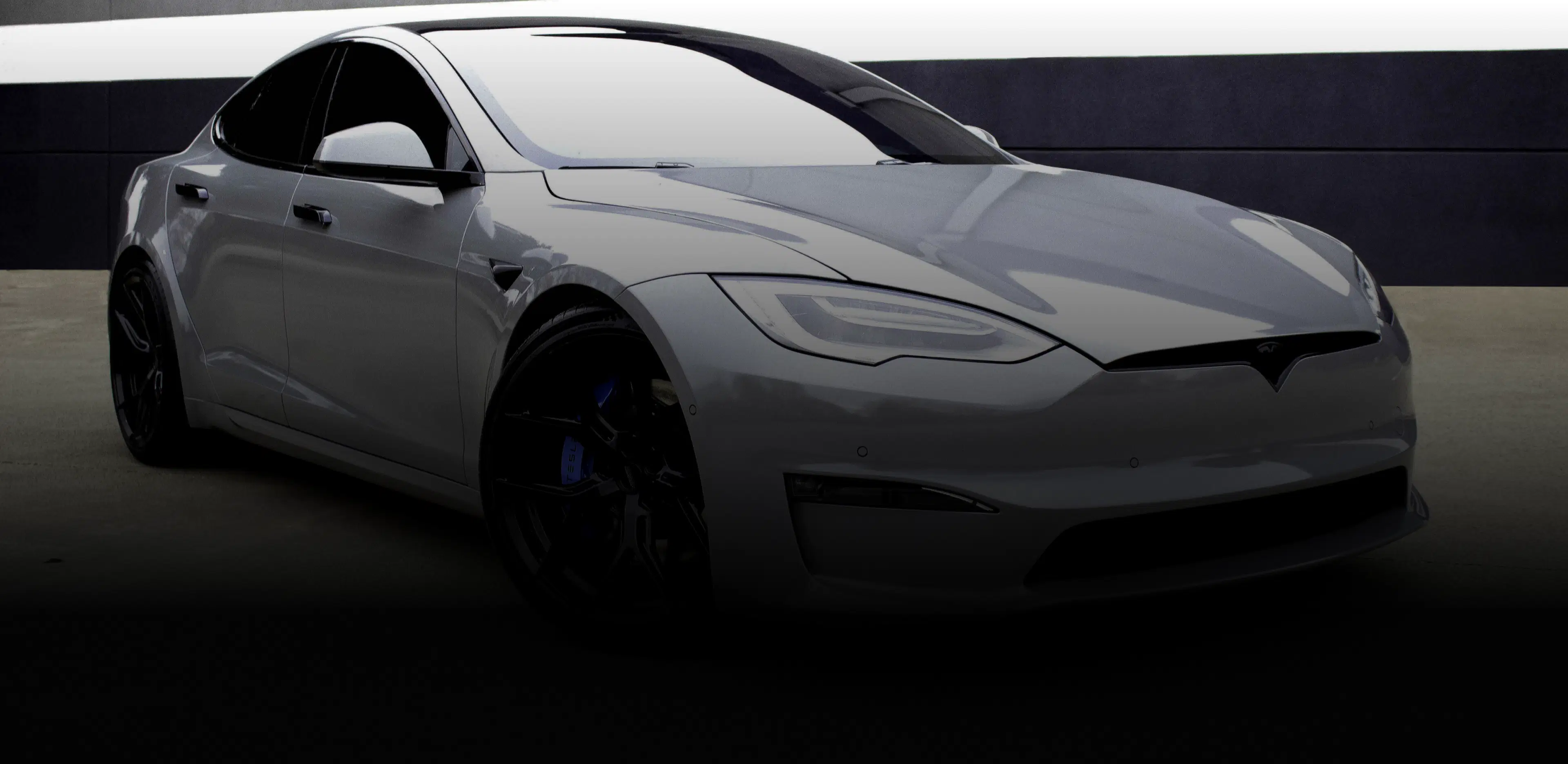 Tesla Model S parked in front of a white building, showcasing Speed Shield USA's automotive PPF and vinyl wrap services.